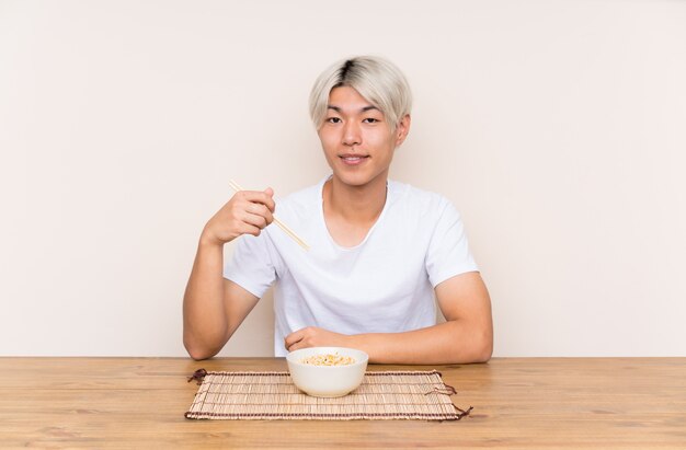 Junger asiatischer Mann mit Ramen in einer Tabelle