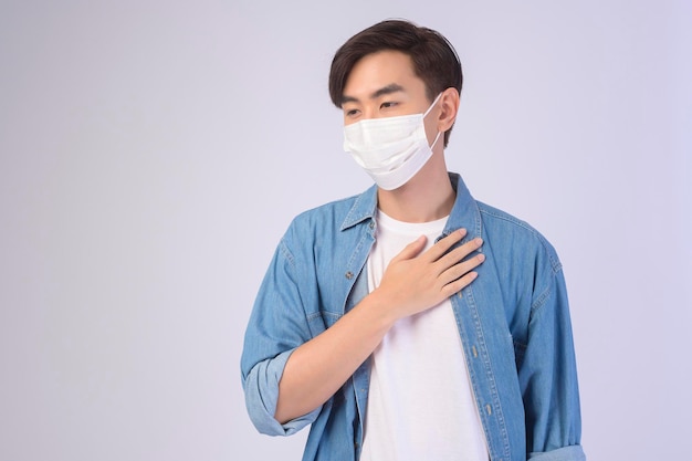Junger asiatischer mann mit schutzmaske über weißem hintergrund studio sicherheitsreisen neues normales soziales distanzierungskonzept covid19 und pandemie