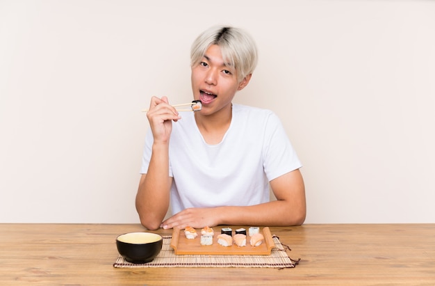 Junger asiatischer Mann mit Sushi in einer Tabelle
