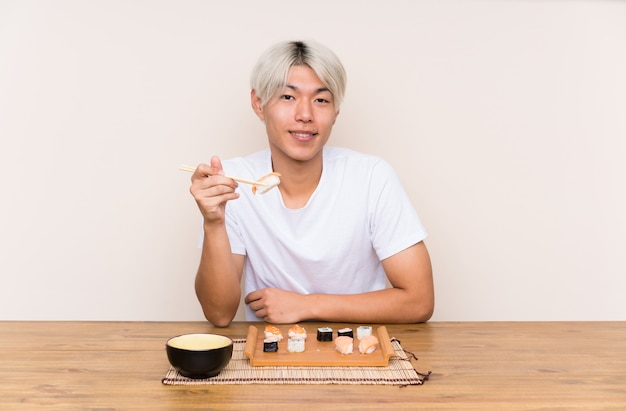Junger asiatischer Mann mit Sushi in einer Tabelle