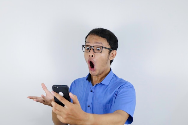 Junger asiatischer mann schockiert und glücklich, als er smartphone schaut