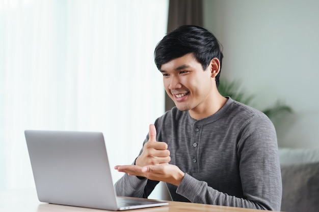 Junger asiatischer mann taub mit laptop-computer für online-videokonferenzgespräche zum lernen und kommunizieren in gebärdensprache behindert.