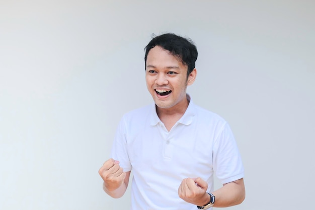 Junger asiatischer Mann trägt graues Hemd mit glücklich lächelndem Gesicht und Daumen hoch