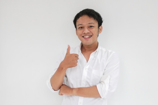 Junger asiatischer Mann trägt weißes Hemd mit glücklich lächelndem Gesicht und Daumen hoch