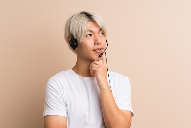 Junger asiatischer Mann über dem lokalisierten Arbeiten mit Kopfhörer