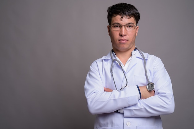 Junger asiatischer Mannarzt gegen graue Wand