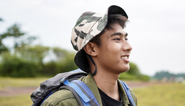 Junger asiatischer Mannreisender mit Rucksack im Reservoir