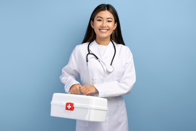 Junger asiatischer Sanitäter in weißer Uniform, der eine Schachtel mit Medizin hält