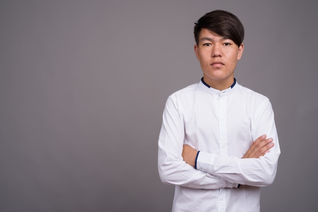 junger asiatischer Teenager, der intelligente Freizeitkleidung gegen graue Wand trägt