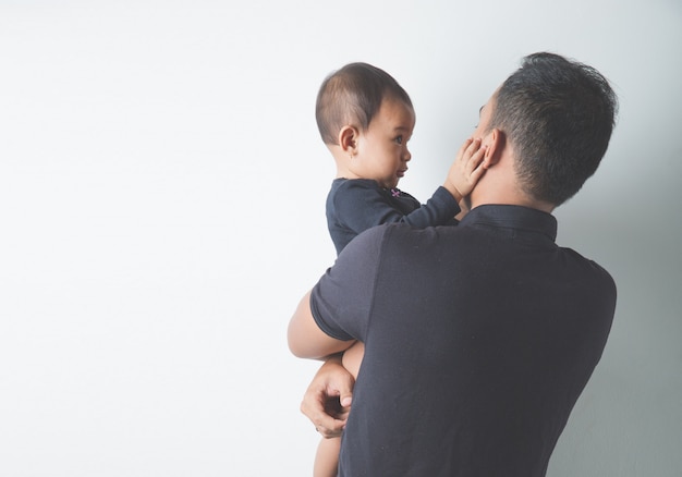 Junger asiatischer Vater, der sein entzückendes Baby hält