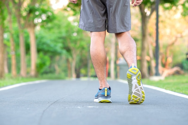 Junger Athletenmann mit Laufschuhen im Park im Freien