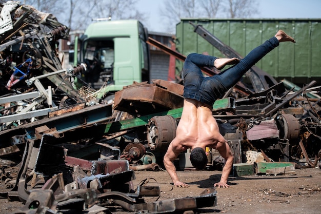 Junger athletischer Mann beim Handstand auf dem Industrieschrottplatz