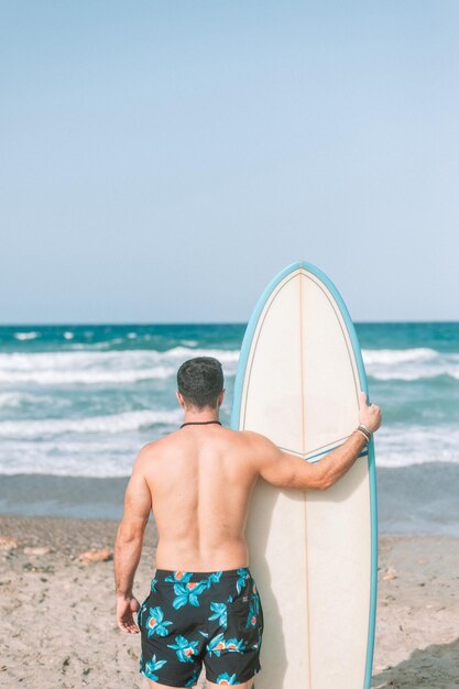 Foto junger athletischer mann, der am strand surft