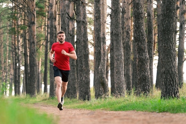 Junger athletischer Mann, der auf einem Waldweg joggt