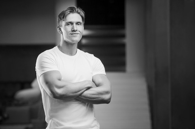 Foto junger athletischer mann, der beim training muskeln im fitnessstudio aufpumpt sport- und gesundheitskonzept