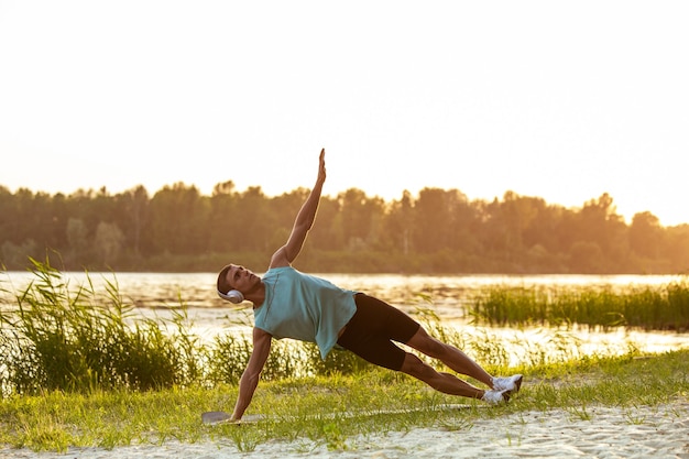 Foto junger athletischer mann, der draußen am flussufer trainiert