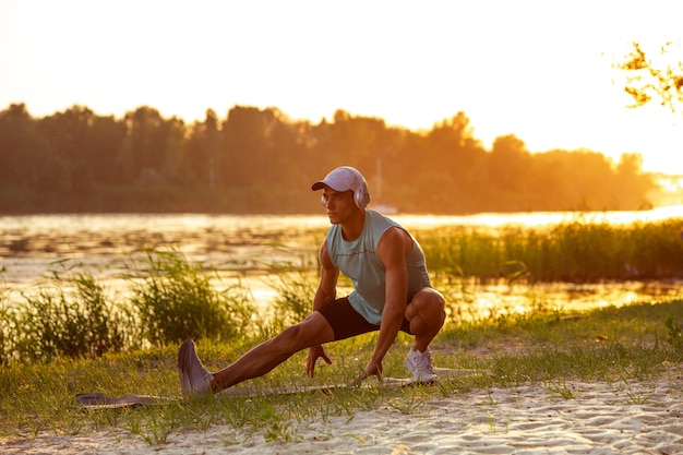 Junger athletischer Mann, der draußen trainiert, am Flussufer trainiert. Konzept des gesunden Lebensstils, Wellness, Sport, Aktivität, Gewichtsverlust. Inspiriert von der Natur.