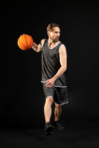 Foto junger athletischer mann, der einen basketball hält