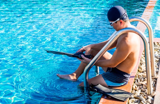 Junger athletischer Mann, der Flossen durch den Pool trägt