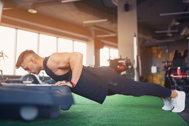 Junger athletischer Mann, der Liegestütze im Fitnessstudio tut