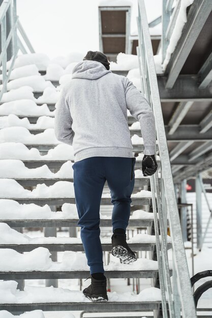 Junger athletischer Mann, der während seines Wintertrainings auf Treppen läuft
