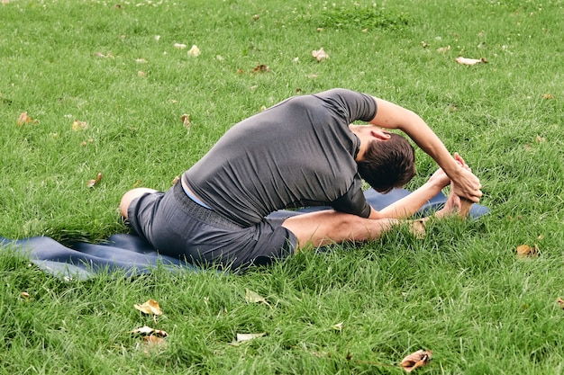 Junger athletischer Mann in der Sportbekleidung, die Yoga im Park tut