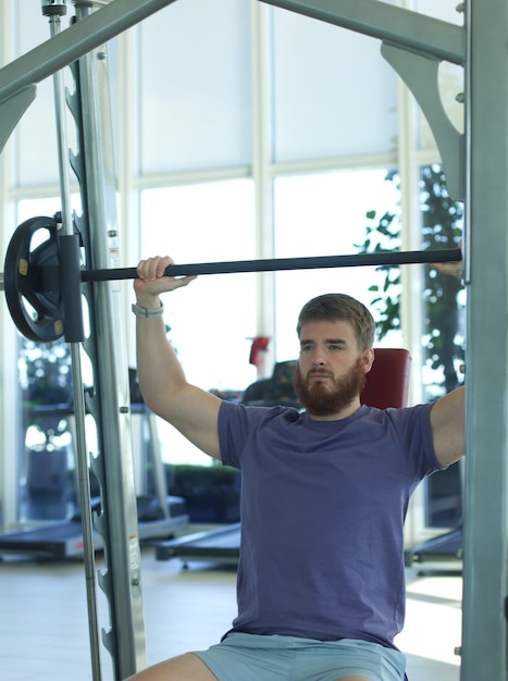 Junger athletischer Mann trainiert im Fitnessstudio und macht Übungen mit der Langhantel