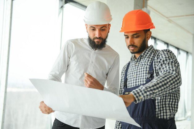 Foto junger attraktiver arabischer wirtschaftsingenieur mit schutzhelm professioneller und industriebauer architekt job worker überprüfung der arbeit in der anlage im innenbereich