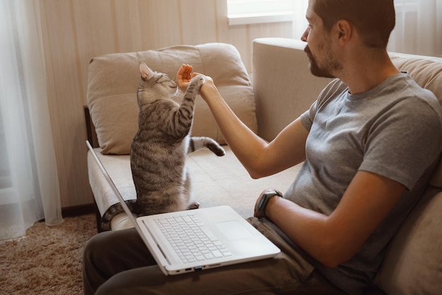 Junger attraktiver lächelnder Kerl surft an seinem Laptop