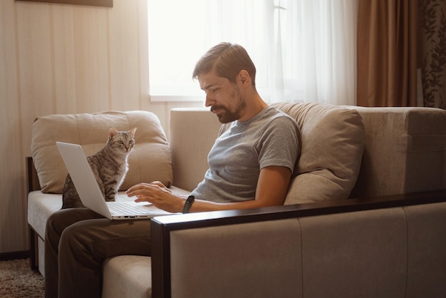 Junger attraktiver lächelnder Kerl surft an seinem Laptop