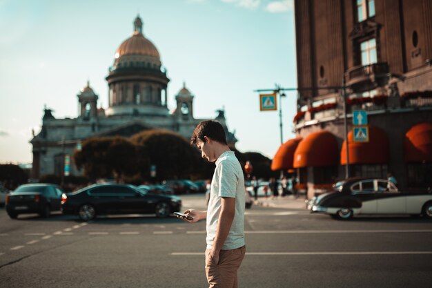 junger attraktiver Mann, der in die Stadt geht und Smartphone verwendet