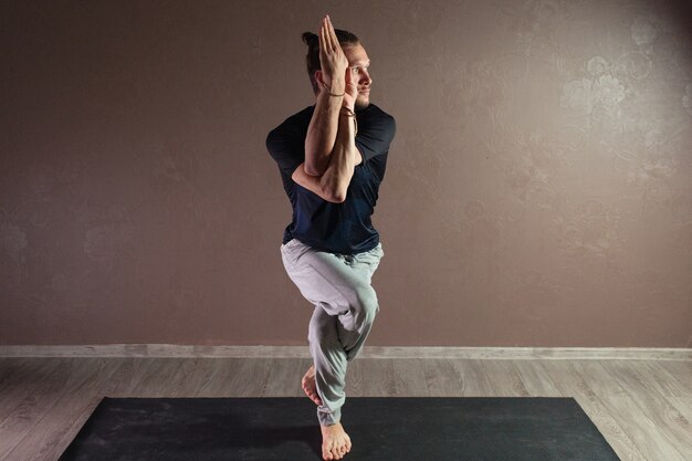 Junger attraktiver Mann, der Yoga tragend Sportbekleidung praktiziert