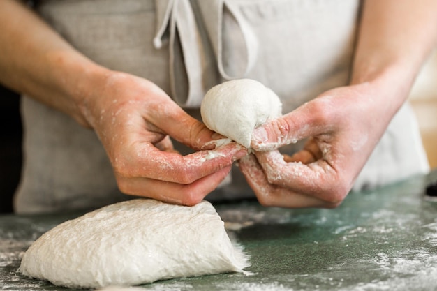 Junger Bäcker, der handwerkliche Sauerteig-Abendessenbrötchen zubereitet.