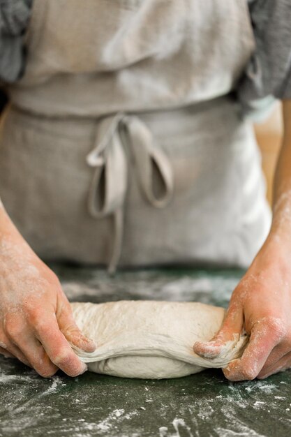 Junger Bäcker, der handwerkliches Sauerteigbrot zubereitet.