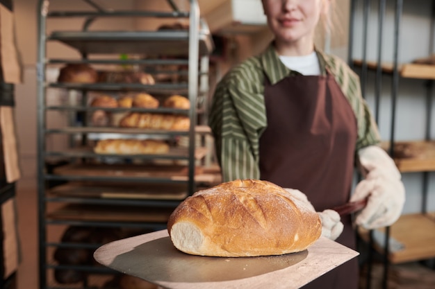 Junger Bäcker in Uniform holt das Brot aus dem Ofen