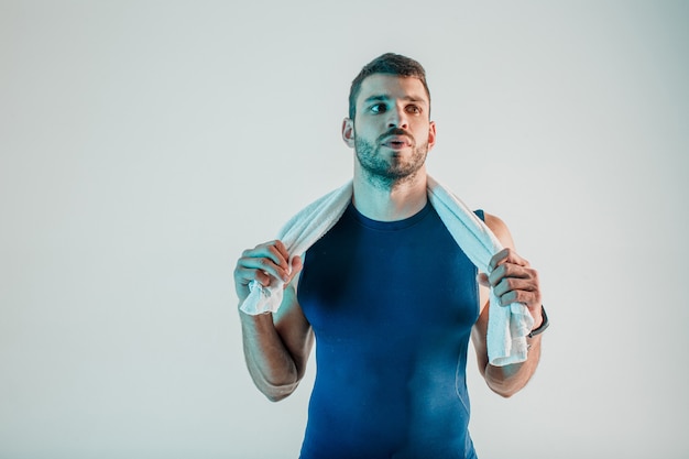 Junger bärtiger europäischer Sportler mit Tuch. Müder Mann nach dem Training. Auf türkisfarbenem Hintergrund isoliert. Studio-Shooting. Platz kopieren