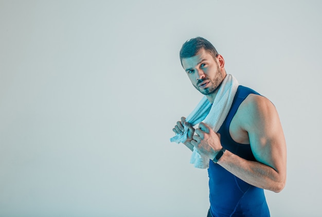 Junger bärtiger europäischer Sportler mit Tuch. Müder Mann nach dem Training und Blick in die Kamera. Auf türkisfarbenem Hintergrund isoliert. Studio-Shooting. Platz kopieren