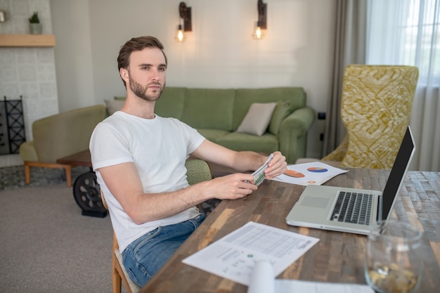 Junger bärtiger Mann, der an einem Laptop arbeitet und konzentriert aussieht