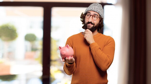 Junger bärtiger Mann mit einem Sparschwein