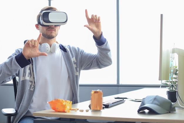 Junger bärtiger Mann mit Virtual-Reality-Brille im modernen Innenarchitektur-Coworking-Studio.