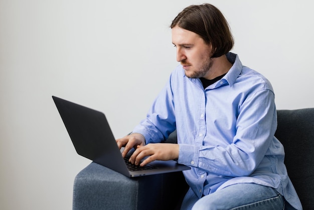 Junger bärtiger Mann ruht auf einer Couch mit einem Laptop