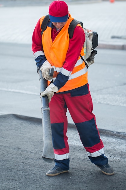 Junger Baumeister auf Asphaltierfertigermaschine während Straßenstraßenreparaturarbeiten