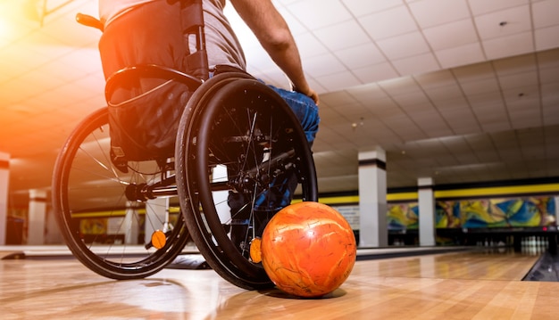 Junger behinderter Mann im Rollstuhl beim Bowling im Club