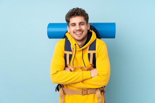 Junger Bergsteigermann mit einem großen Rucksack auf blauem Lachen