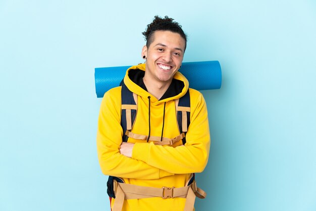 Junger Bergsteigermann mit einem großen Rucksack über isoliertem blauem Lachen