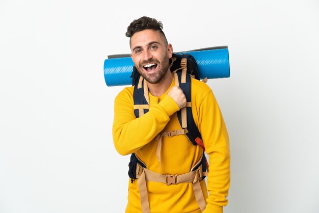 Junger Bergsteigermann mit einem großen Rucksack über isolierter Wand, die einen Sieg feiert