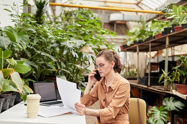 Junger Besitzer einer Orangerie oder eines Blumenladens, der Daten in Rechnungen überprüft