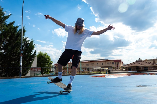 Junger blonder Junge mit langen Haaren, der Skateboard-Tricks im Skatepark durchführt?