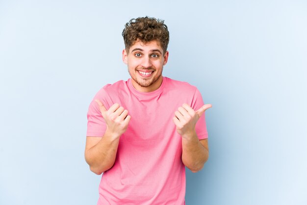 Junger blonder kaukasischer Mann des lockigen Haares isoliert, beide Daumen hoch, lächelnd und zuversichtlich.