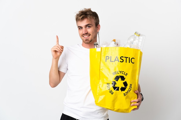 Junger blonder Mann, der einen Recyclingbeutel voll Papier hält, um lokalisiert auf weißem Hintergrund zu recyceln, der eine große Idee aufzeigt